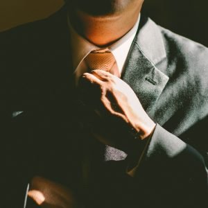 A man in a black suit loosening his tie